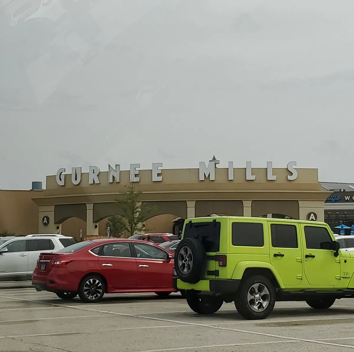 Gurnee Mills sign above Entrance A with parked vehicles in front
